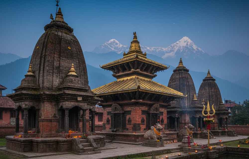 A serene, detailed, and high-quality image showcasing the famous Shiva temples of Nepal, such as the pagoda-style Pashupatinath Temple on the banks of the Bagmati River and the natural cave shrine of Halesi Mahadev. The temples are depicted surrounded by lush green mountains and sacred rivers, without any human figures, evoking a peaceful and spiritual atmosphere suitable for the holy month of Karthika Masam.
