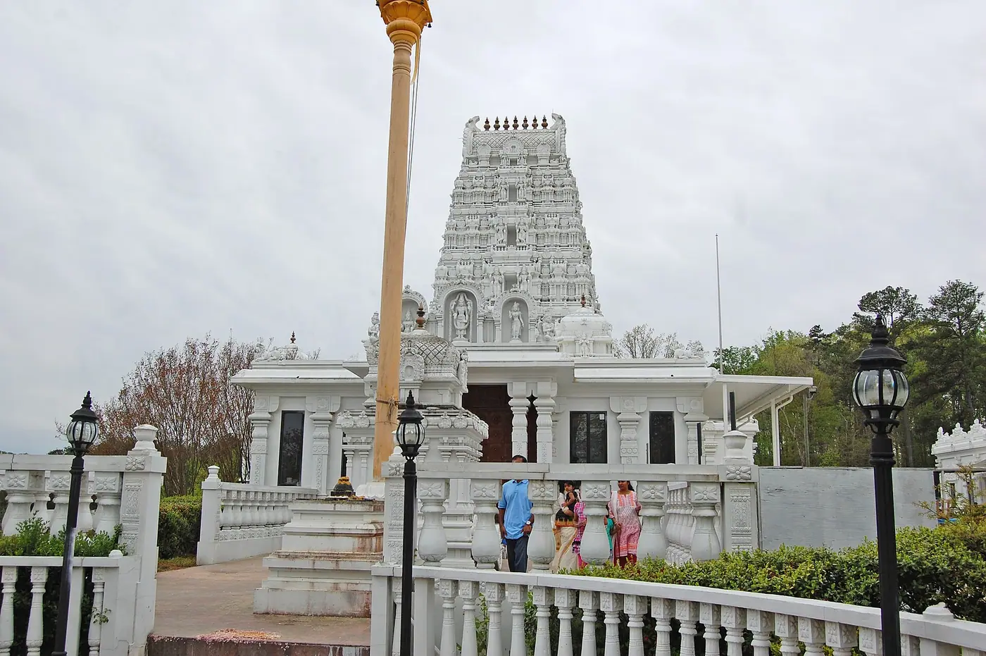 White tiered gopuram and entrance of the Venkateswara temple at the Hindu Temple of Atlanta in Riverdale, Georgia, with a flagstaff in front