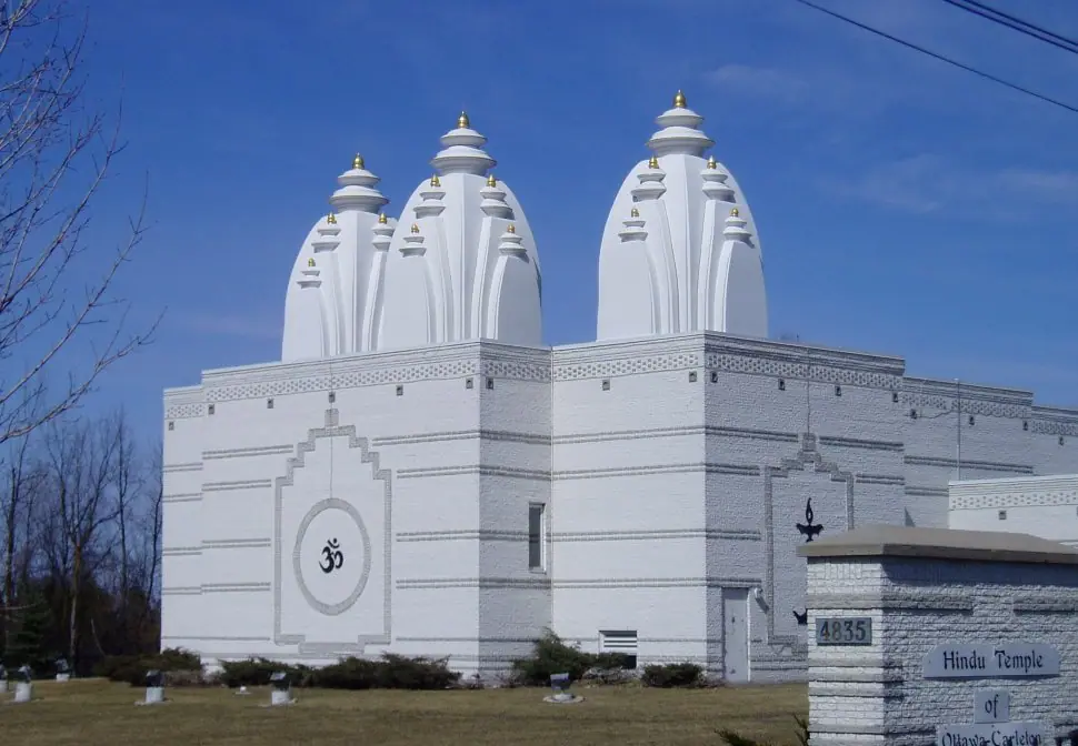 White shikhara towers and exterior of the Hindu Temple of Ottawa-Carleton beside its 4835 street sign