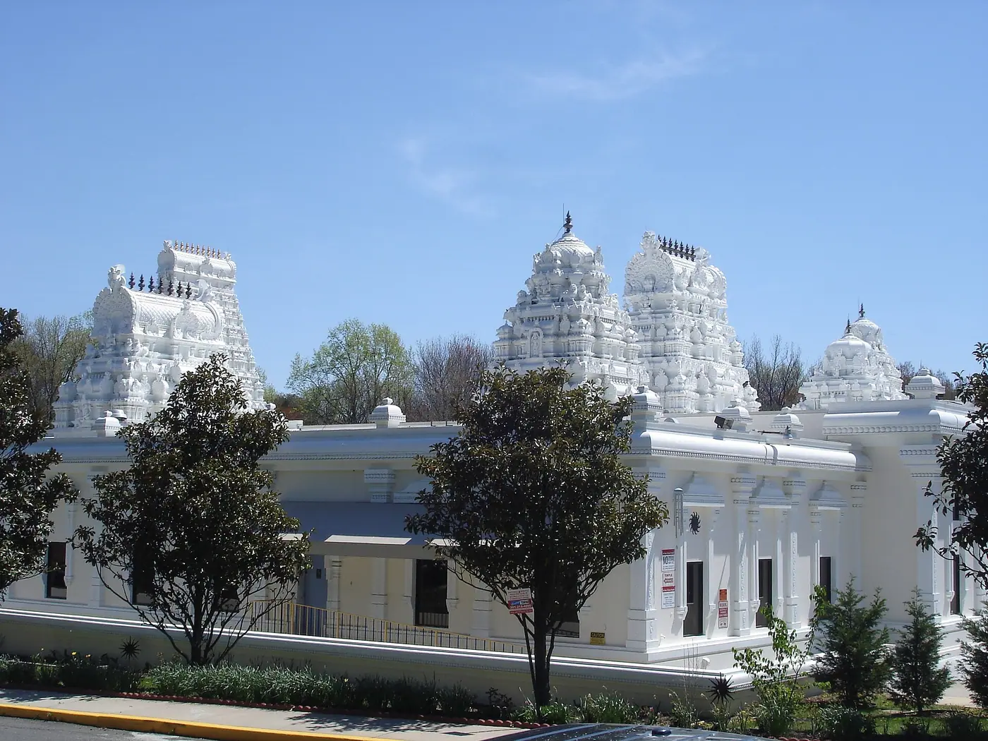 White gopurams and exterior walls of Sri Siva Vishnu Temple in Lanham, Maryland, under a blue sky