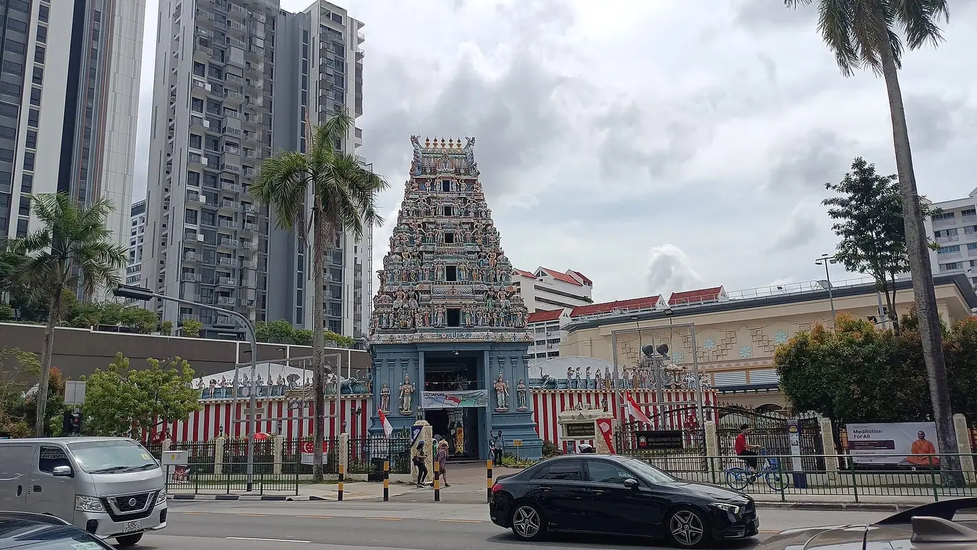 Colourful five-tier gopuram and red-and-white striped compound wall of Sri Srinivasa Perumal Temple on Serangoon Road, Singapore, with apartment towers behind