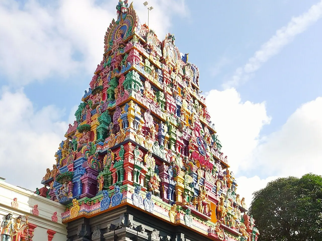 Colourful South Indian gopuram with a grey stone base at Sri Thendayuthapani Temple on Tank Road, Singapore, with shoe racks and steps at the entrance